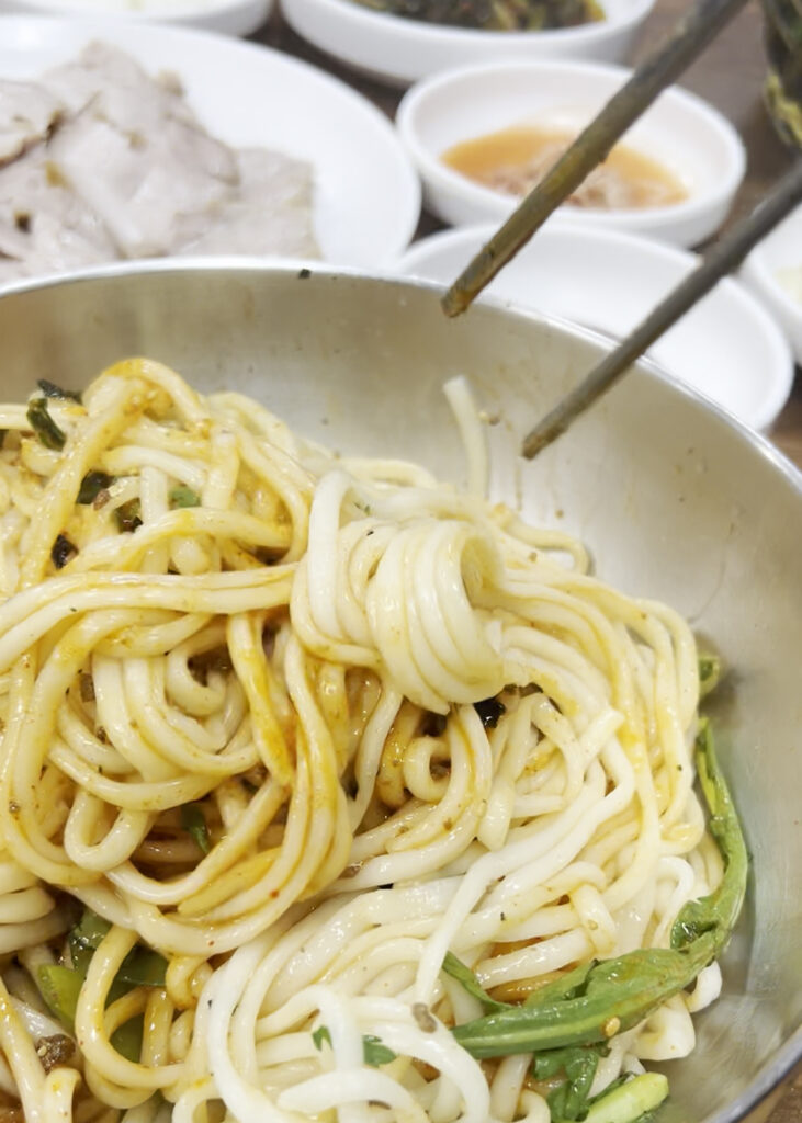 양념에 비벼진 대선칼국수의 비빔칼국수 면발 클로즈업. A close-up of the noodles from Daeseon Kalguksu's bibim-kalguksu (spicy mixed noodles).