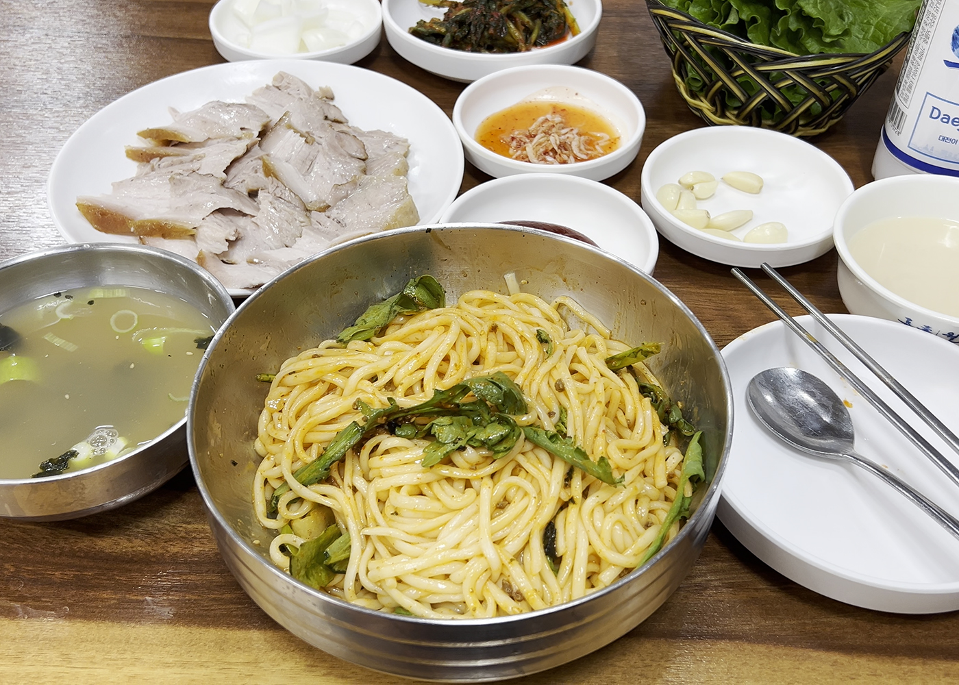 대선칼국수의 비빔칼국수와 함께 수육, 막걸리, 국물, 기본 반찬이 모두 차려진 전체 상차림. A full table setting at Daeseon Kalguksu, featuring bibim-kalguksu, suyuk, makgeolli, and various side dishes.