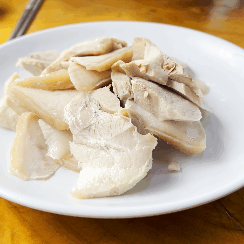A close-up shot of a white plate filled with thinly sliced, tender jeyuk (boiled pork) at Pildong Myeonok.