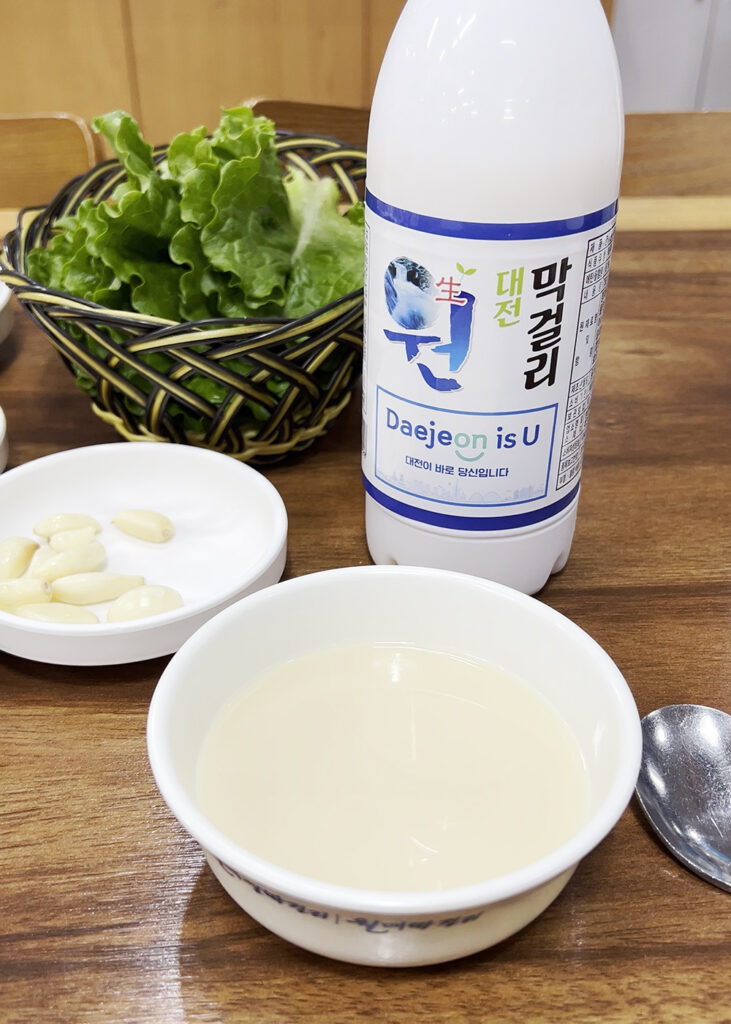 대전생막걸리를 그릇에 따라 마시는 모습. Pouring Daejeon Saeng Makgeolli (Korean rice wine) into a traditional bowl.