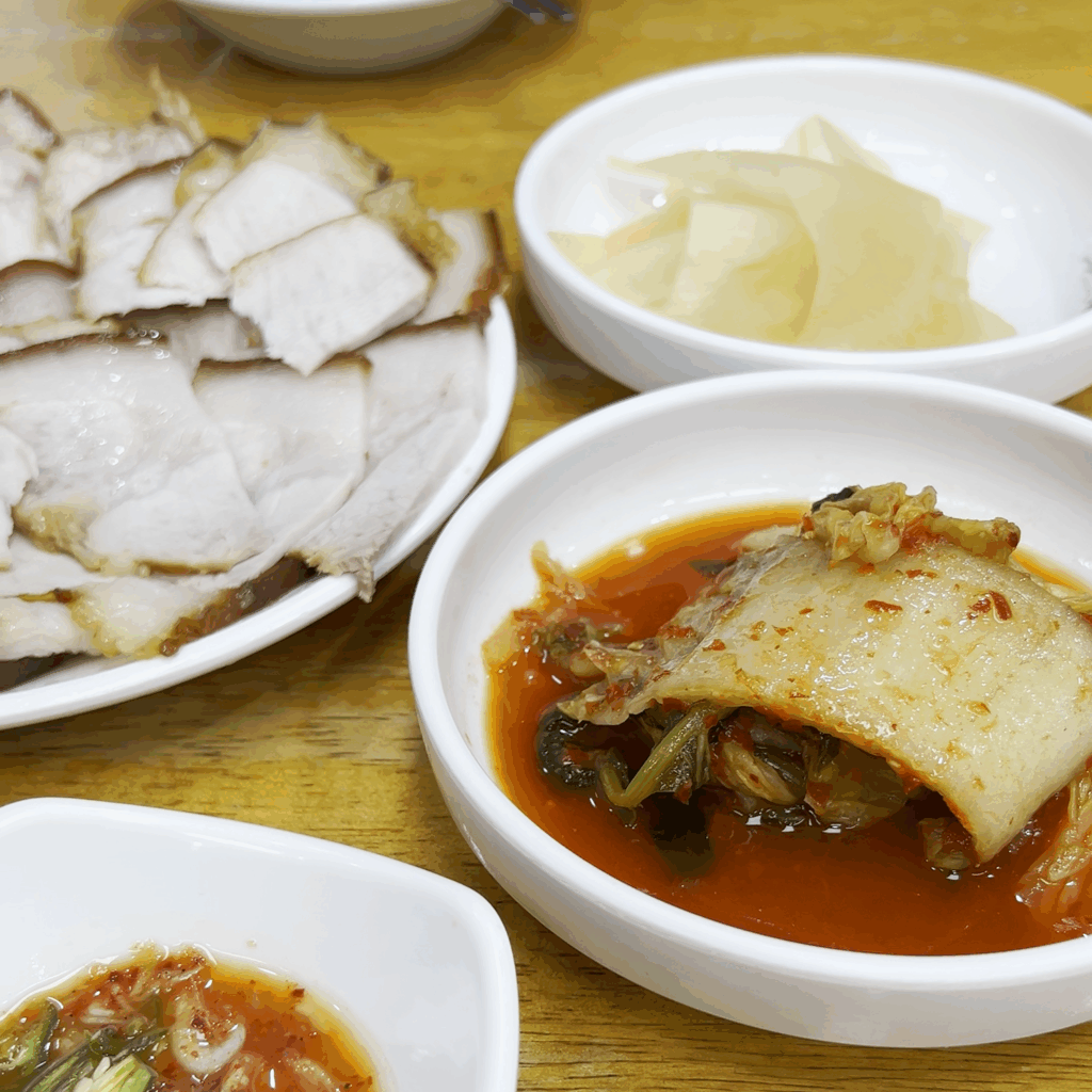 평남면옥의 돼지고기 편육과 함께 곁들여 먹는 묵은지(김치) 클로즈업. A close-up of the aged kimchi served alongside the pork pyeonyuk at Pyeongnam Myeonok.