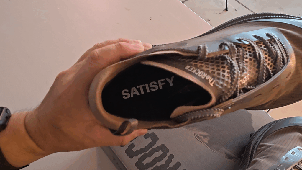 새티스파이(SATISFY)와 'The Rocker' 문구가 프린트된 더 락 팔콘 신발의 안쪽 인솔(깔창) 모습. The inner insole of The Rock Falcon shoe, printed with the SATISFY and 'The Rocker' text.