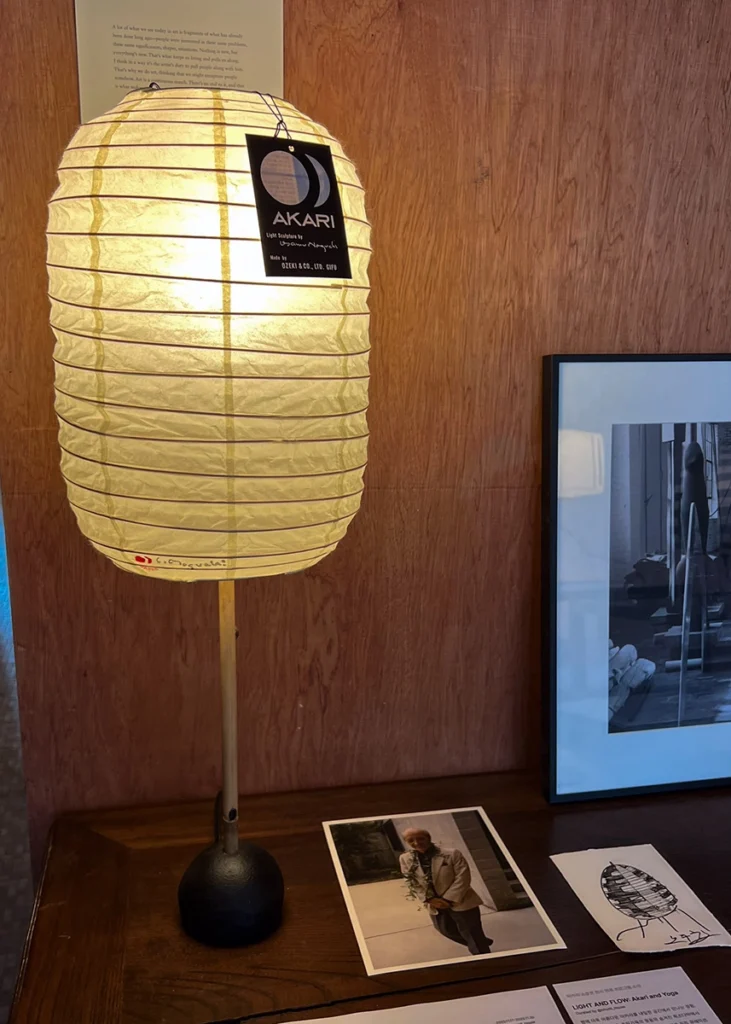 아카리 테이블 램프와 이사무 노구치 사진이 함께 전시된 장면 Akari table lamp displayed alongside a photo of Isamu Noguchi
