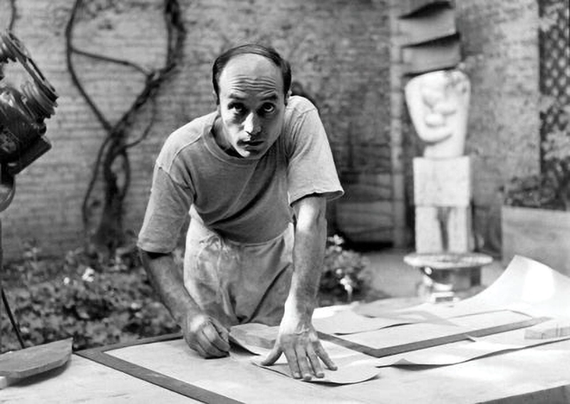 작업대 위에서 종이 디자인 작업을 진행 중인 젊은 시절의 이사무 노구치 Young Isamu Noguchi working on paper design at his studio table