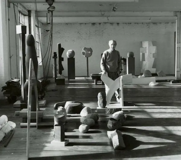 조각 작품들 사이에서 작업 공간에 서 있는 이사무 노구치의 스튜디오 모습 Isamu Noguchi standing in his sculpture studio surrounded by artworks